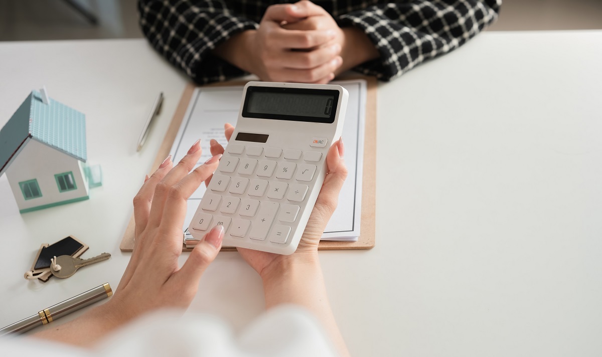 Close-up of calculator and house model with business documents. Concept of real estate finance and calculation